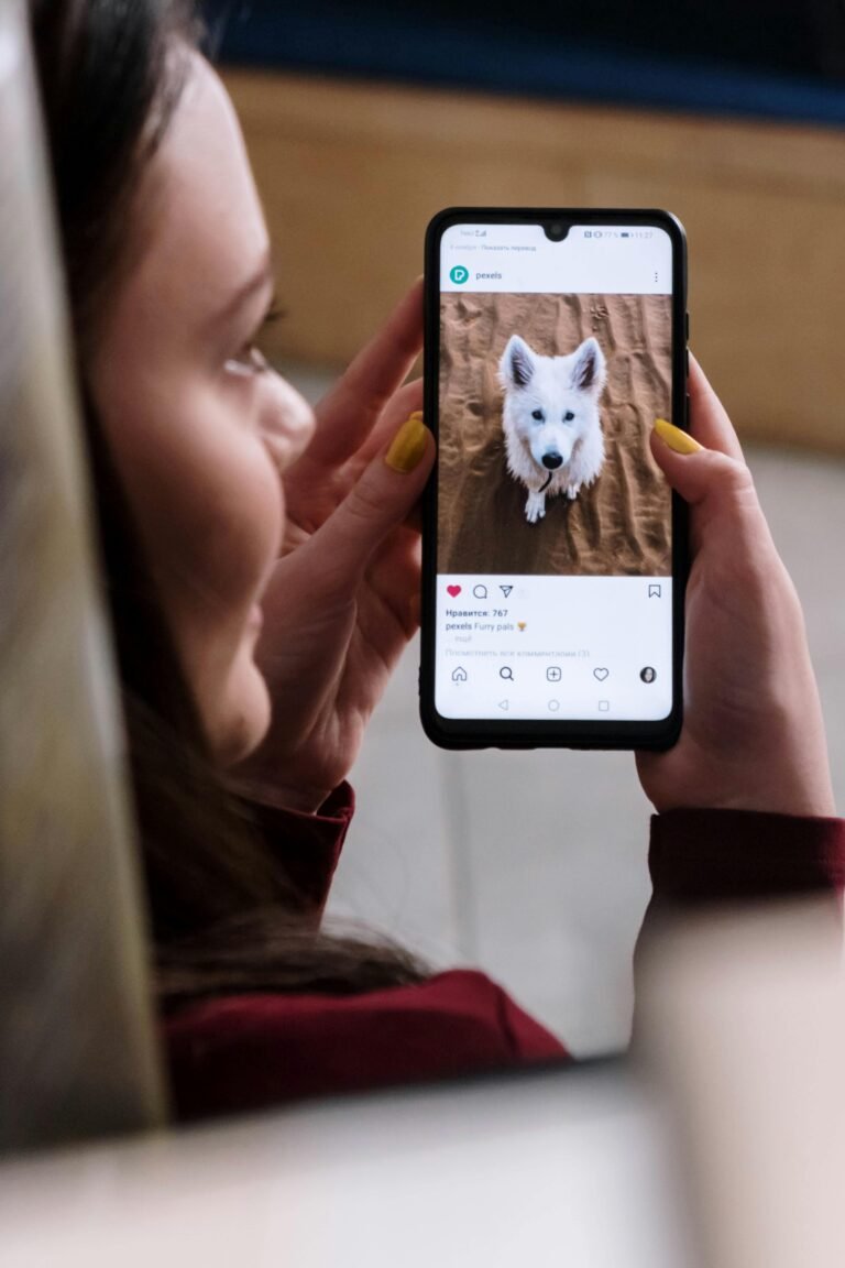 A young woman holding a smartphone displaying a cute puppy on social media.