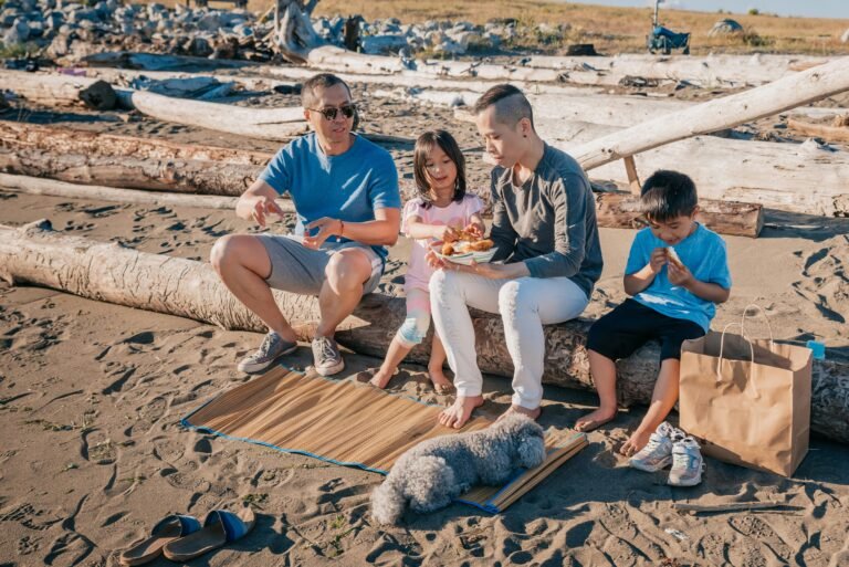 A family enjoying a joyful picnic on a sunny beach with their dog.
